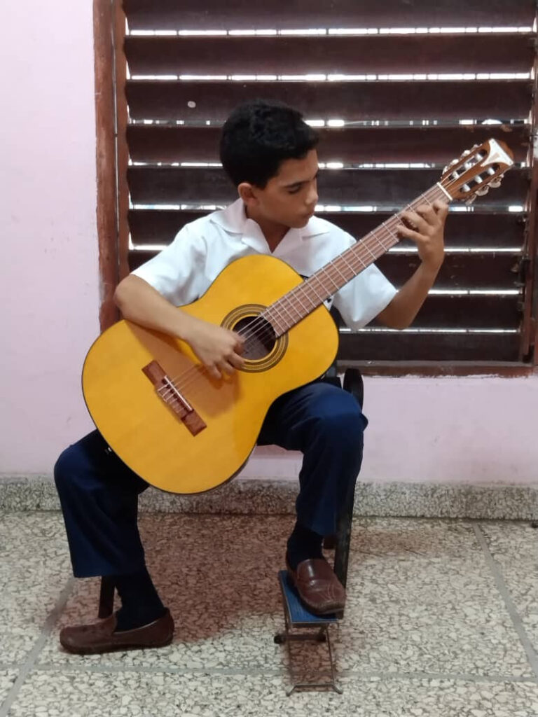 a student at the National School of Arts in Cuba plays a new Epiphone acoustic guitar at the Gibson Gives donation event.