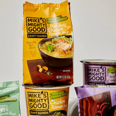 Mike’s Mighty Good ramen products including Fried Garlic Chicken pillow pack, Spicy Pork Tonkotsu cup, and assorted organic instant ramen varieties displayed together